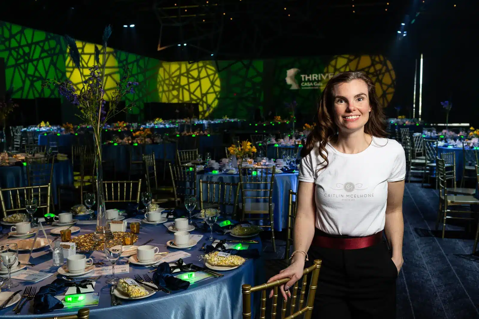Event planner Caitlin Mcelhone standing beside decorated gala table during Edmonton charity event setup